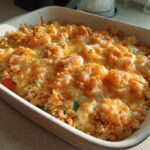 A close-up of a golden-brown Shrimp Casserole Recipe in a white baking dish, topped with melted cheese and crispy breadcrumbs.