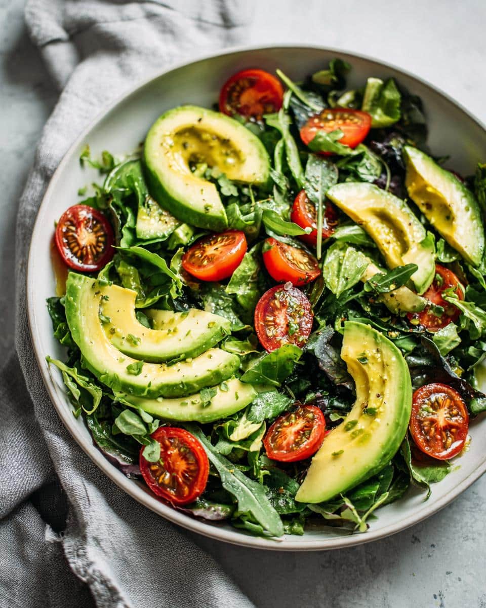 A vibrant bowl of Fresh Super Simple Healthy Lunches featuring a green salad with sliced avocado and halved cherry tomatoes.