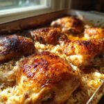 Close-up of a baking dish filled with golden brown Oven-Baked Comfort Food: Chicken and Rice, with crispy chicken skin.