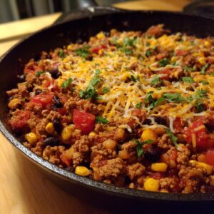 A close-up of a Protein-Packed Healthy Ground Turkey Taco Skillet in a cast iron pan, topped with melted cheese and fresh cilantro.