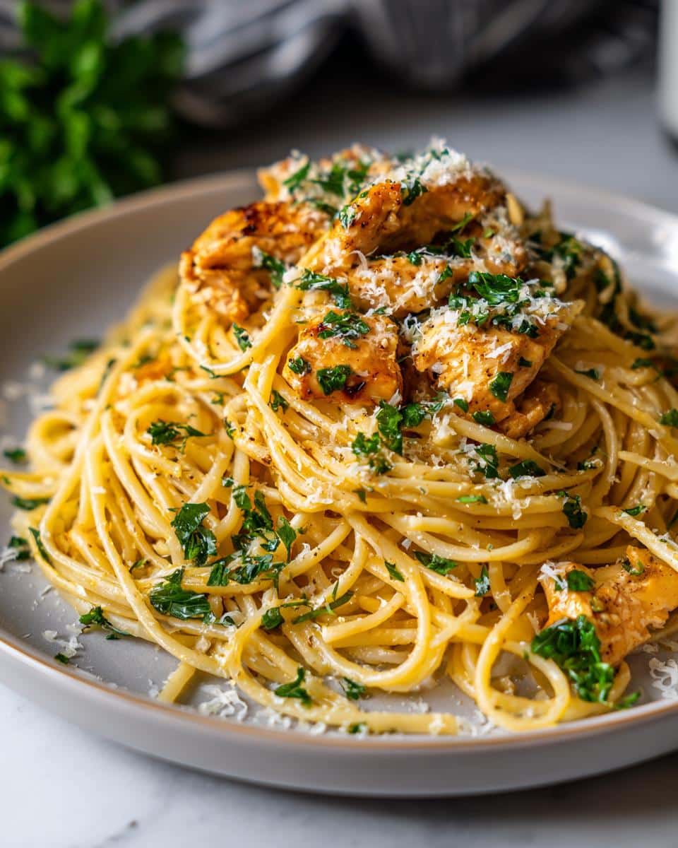 Close-up of a plate of Quick Garlic Chicken Pasta, garnished with fresh parsley and grated Parmesan cheese.